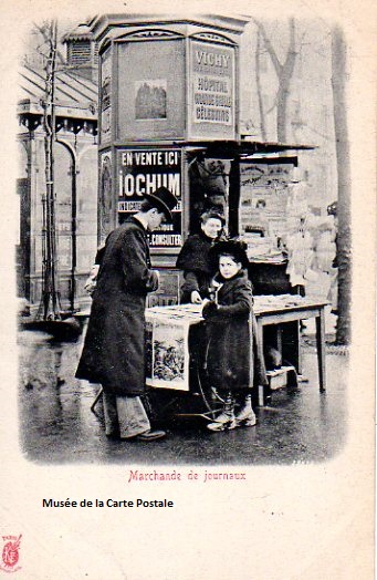Carte postale ancienne représentant un des anciens kiosques à journaux, et sa marchande.