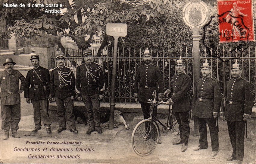 Carte postale ancienne représentant un poteau à la frontière franco-allemande avec des gendarmes et douaniers.